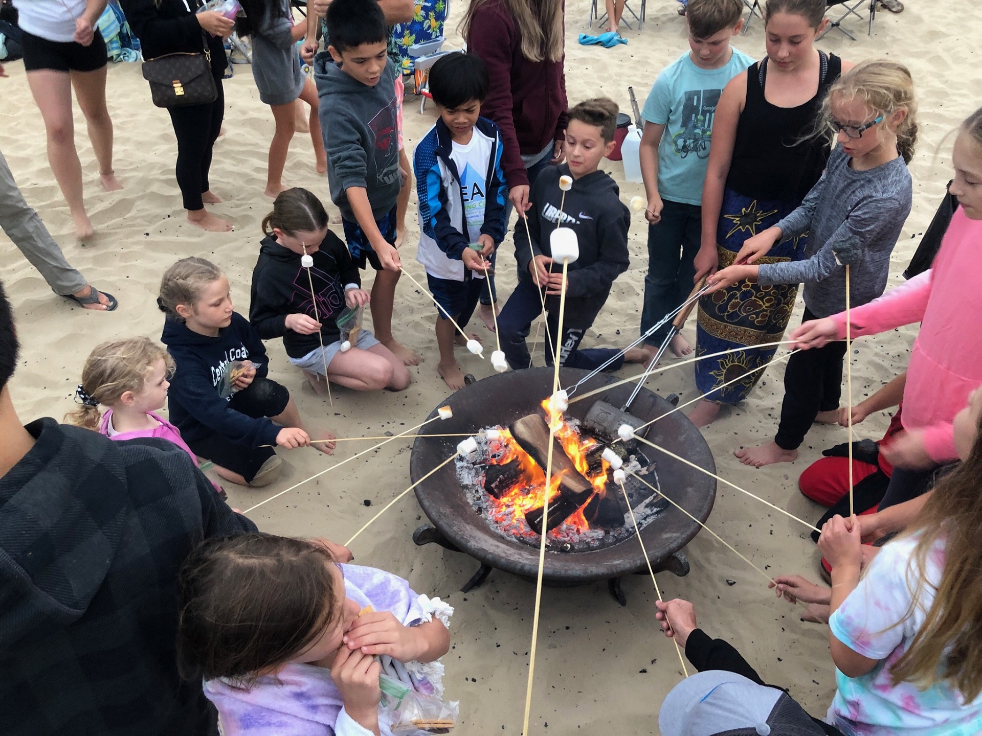 group of kids roasting marshmallows around camp fire